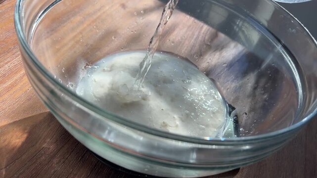 Adding Water to Sourdough Starter in Glass Bowl