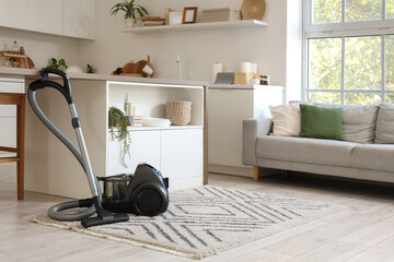 Interior of kitchen with vacuum cleaner, table and sofa
