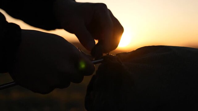 Hands Tying Backpack Bag Closure at Golden Hour Sunset