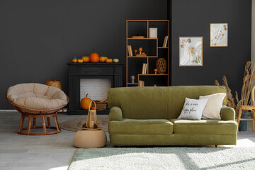 Naklejka premium Interior of modern living room with green sofa, black fireplace and shelving unit. Autumn concept