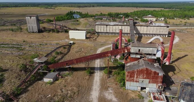 Rusty storage tanks and industrial towers of abandoned phosphate facility in Florida.