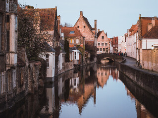 Naklejka premium Scenic view of the famous canal in Bruges (Brugge), Belgium, with medieval brick houses reflecting in the water and a stone bridge.
