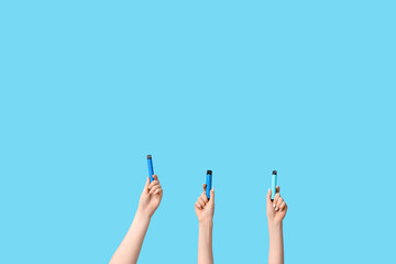 Many hands holding electronic cigarettes on blue background