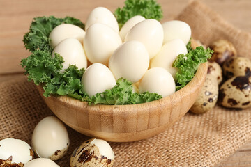 Naklejka premium Bowl with fresh boiled quail eggs and lettuce on wooden background