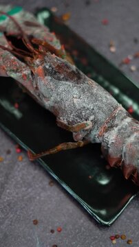 a lobster with spices on a black rectangle plate