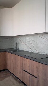 a marble brown and white kitchen with white cupboards and a black countertop 