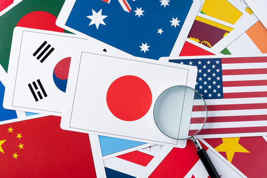 世界の国旗の中心に置いた日本の国旗のカードと虫眼鏡