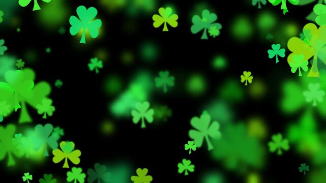 St Patricks day background with shamrocks in various greens floating outward on black. Three leaf clover particles drifting by for a green background to celebrate St Patrick day.