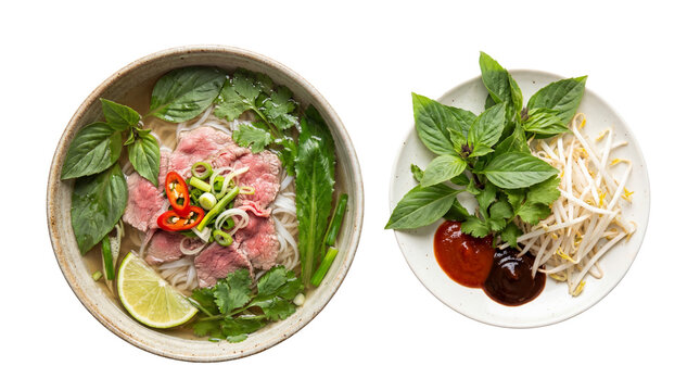 Vietnamese Pho Bo with rare beef, rice noodles, fresh herbs, and lime in a bowl, with a side plate of bean sprouts, basil, and sauces, isolated on white background