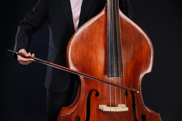Girl playing double bass on black background, closeup