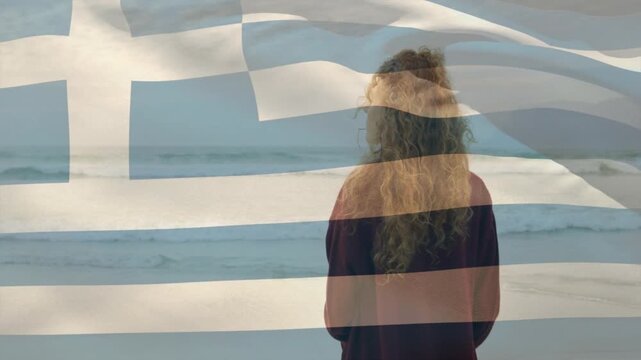 On playback woman standing shore facing sea, Greek flag overlaying woman, rippling, evoking travel