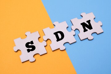 Obraz premium SDN word alphabet letters on wooden puzzle. SDN acronym for Software Defined Networking