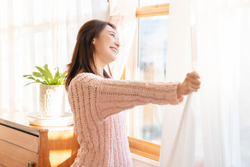 カーテンを開ける女性