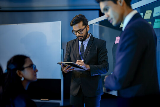 Corporate strategy consultants brainstorming digital transformation roadmap milestones. Business executives analyzing organizational kpi objectives via visual mapping technique.