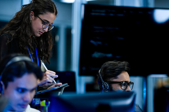 IT service management specialist resolving technical support tickets with supervisor. Female operations manager auditing workstation workflow efficiency strategies.
