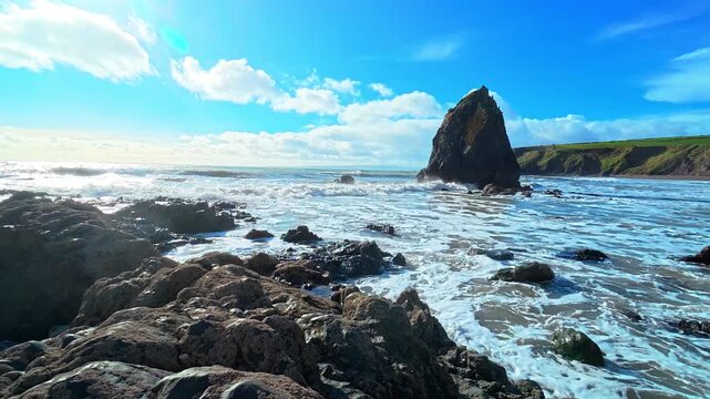 Ireland epic locations waves coming ashore with sea stack and bright spring sky Waterford epic locations