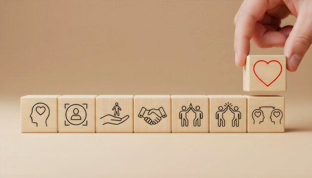 Hand placing a heart icon block on a line of social responsibility and community building blocks