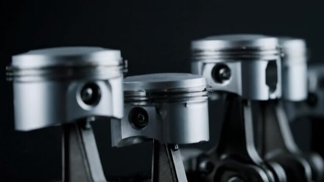 Close-up of a row of car engine pistons moving up and down in a dark studio.