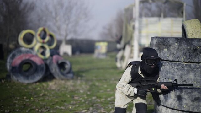 Paintball players engage in a tactical game. Participants enjoy active recreation on a battleground with strategic cover.
