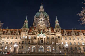 Obraz premium Experience the beauty of Hannover s New Town Hall at night. This iconic structure illuminates the skyline, representing the charm of Hannover, Lower Saxony, Germany.
