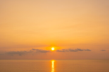 Fototapeta premium nature sky breathtaking golden sunset over a calm ocean, with the entire sky and water bathed in brilliant shades of yellow and orange. Streaky clouds enhance the dramatic displa