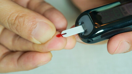 Woman's hands checking diabetes and hyperglycemia with digital blood sugar meter. Healthcare and...