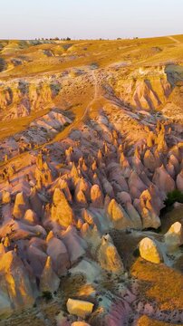 Vertical video. Goreme, Nevsehir, Turkey. Detailed aerial shot of Devrent Valley revealing intricate erosion details and rock textures during evening light.. Aerial View. Rich colors
