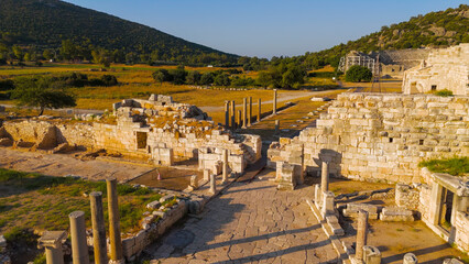 Obraz premium Gelemis, Turkey. Aerial flight from Colonnaded Street over city wall to panorama of Patara ancient city with theatre, parliament, beach and lighthouse. Aerial View