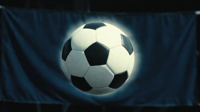 Soccer ball is in the air above a blue flag. The flag is large and the ball is small