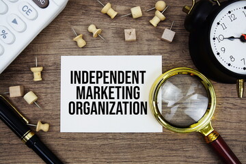 Independent Marketing Organization text written on notepad with pen, alarm clock, magnifying glass...