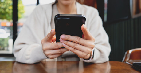 Woman holding and using a smartphone. The image highlights modern mobile communication, social media browsing, messaging and digital lifestyle.