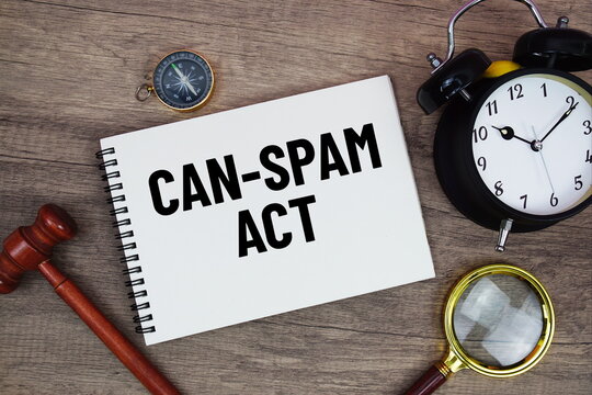 CAN-SPAM Act message written on notepad with alarm clock, wood gavel and magnifying glass flat lay on wooden background