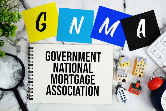 Government National Mortgage Association text written on notepad with house model, magnifying glass, calculator and alarm clock on marble background