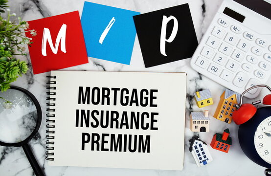 MIP Mortgage Insurance Premium text written on notepad with house model, magnifying glass, calculator and alarm clock on marble background