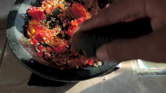grinding chili peppers to make sambal, using a mortar