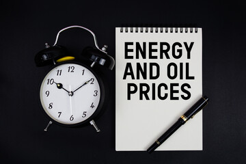 Energy and Oil Prices text written on notepad with alarm clock top view on black background