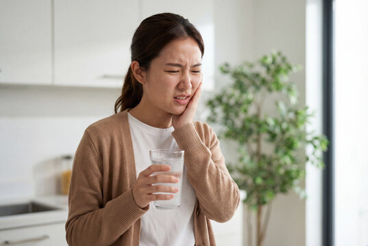 Asian woman with sensitive teeth feeling sudden pain from cold water