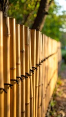 A bamboo fence with black wire, surrounded by greenery