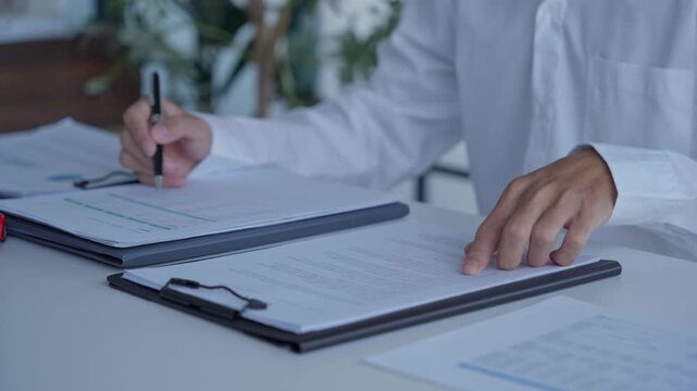Businessman holding pen checking document on working desk