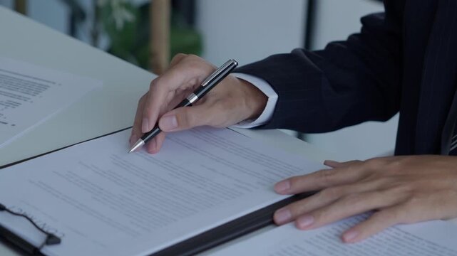 Lawyer holding pen checking documents with gavels on desk