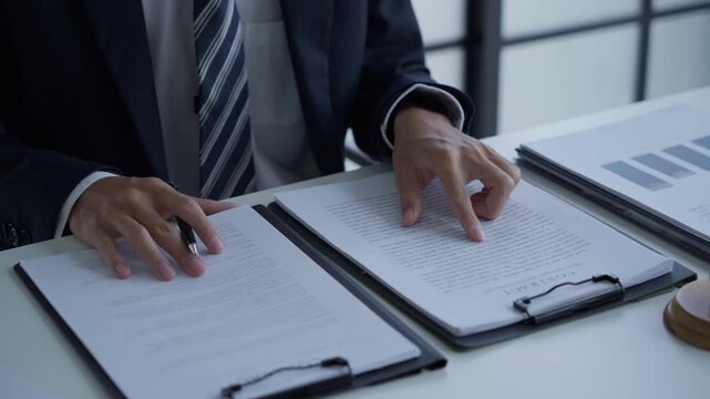 Lawyer holding pen checking documents with gavels on desk