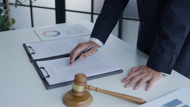 Lawyer holding pen checking documents with gavels on desk