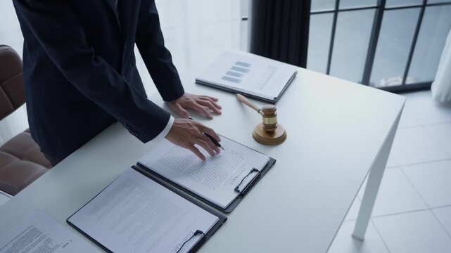 Lawyer holding pen checking documents with gavels on desk