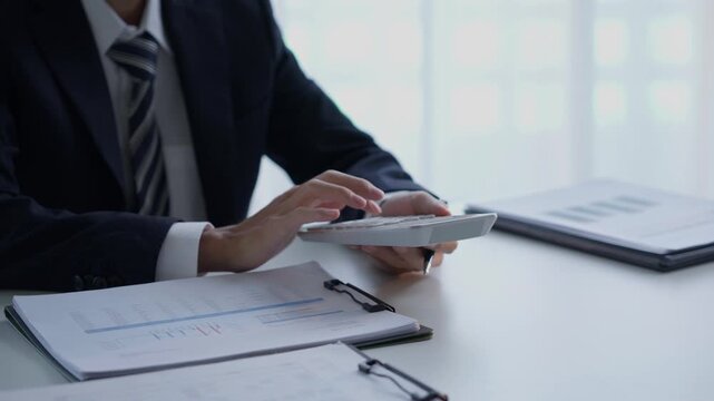 Accountant in suit do accounting and pressing calculator