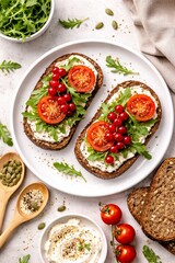 Delicious toast with cream cheese fresh tomatoes and leafy greens on a white plate surrounded by ingredients