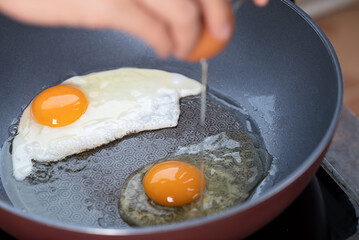 Obraz premium Hand cracking a fresh egg into a frying pan for fried egg