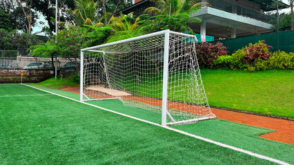 Fototapeta premium A soccer goal is on a field with green grass. The goal is white and has a net
