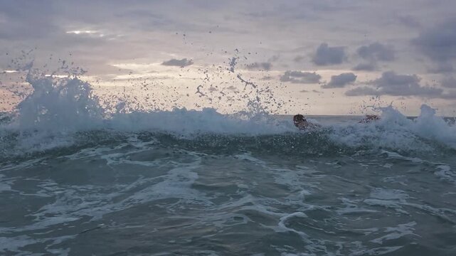 Surfer enters the water and faces backwash wave crushing next to him