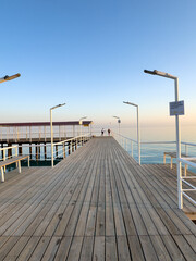 Fototapeta premium Pier at Issyk Kul Lake in Kyrgyzstan. Calm water surface, minimal composition and warm sunset light.