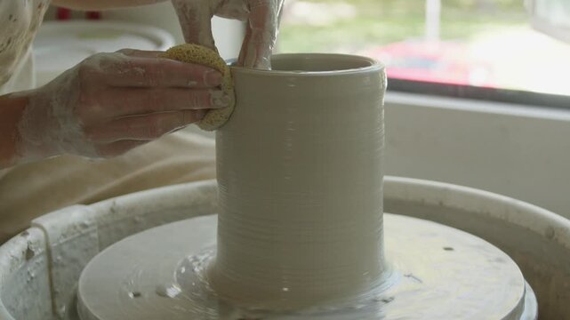 Slow motion footage of a vase being formed on a pottery wheel